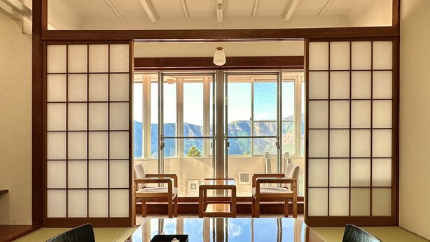 Una habitación tradicional japonesa con suelo de tatami, una mesa baja y puertas correderas.