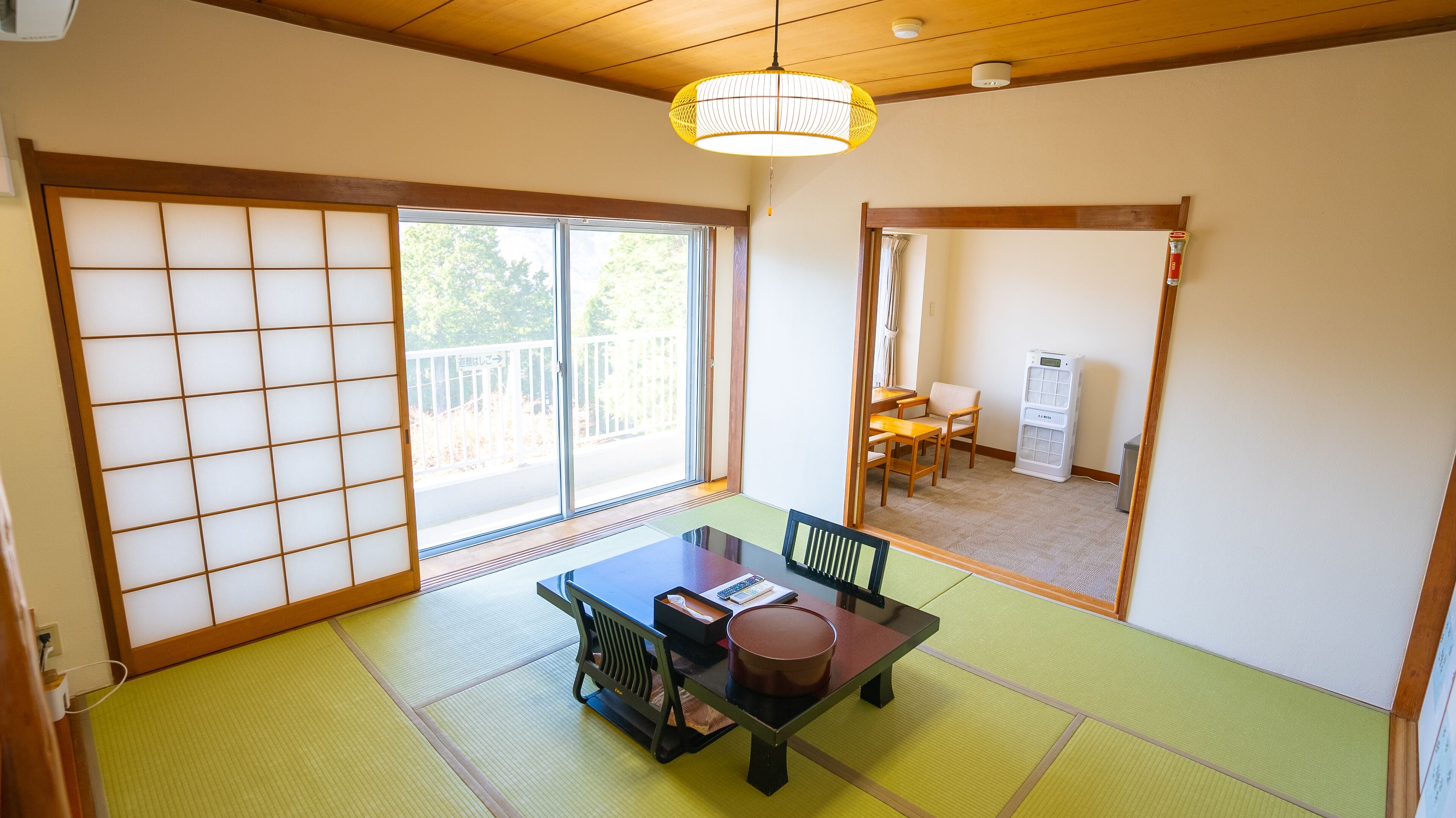 A traditional Japanese room with tatami flooring, a sliding door, a table with chairs, and a ceiling fan.
