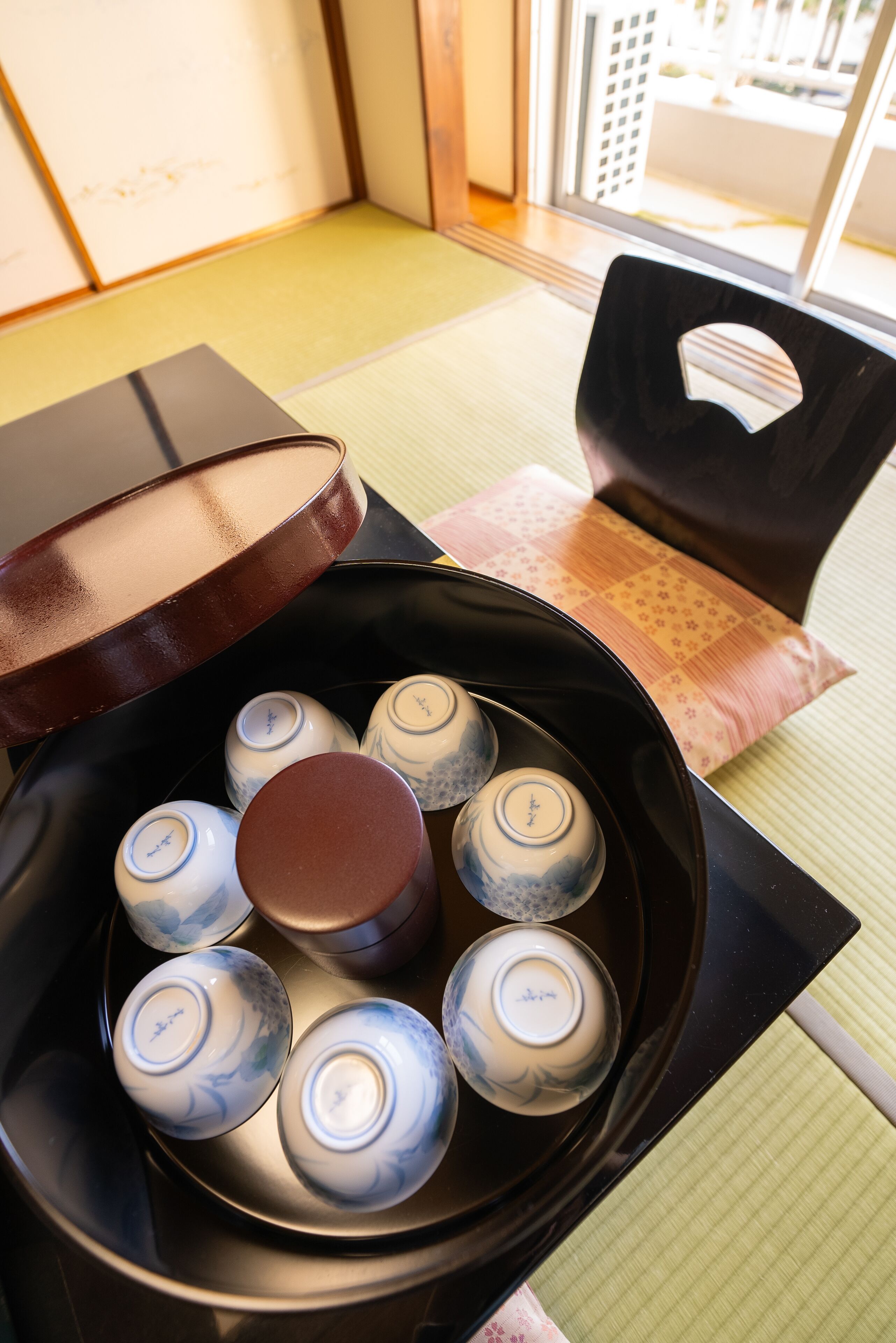 A tatami mat room with a traditional Japanese tea set on a table.
