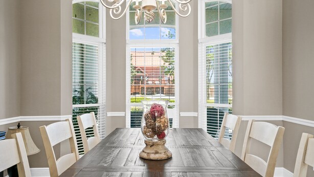 A dining room with a wooden table, white chairs, and a chandelier. - Private Pool Home on the East End of PCB – Minutes to the Beach (Panama City)