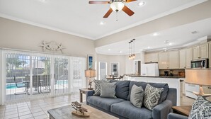 A spacious living area with a gray sofa, wooden coffee table, and a ceiling fan. - Private Pool Home on the East End of PCB – Minutes to the Beach (Panama City)
