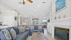 A spacious living room with a large sofa, a coffee table, and a fireplace. - Private Pool Home on the East End of PCB – Minutes to the Beach (Panama City)
