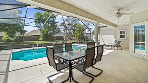 A covered patio with a glass enclosure, a pool, and outdoor furniture. - Private Pool Home on the East End of PCB – Minutes to the Beach (Panama City)
