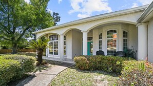 A building with a covered porch, large windows, and a well-maintained garden. - Private Pool Home on the East End of PCB – Minutes to the Beach (Panama City)