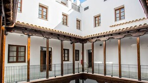 A courtyard with white walls, wooden beams, and multiple windows. - PALACIO BUENAVISTA LUXURY APARTMENTS B.2 (Sevilla)