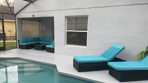 A pool area with a seating arrangement and a covered section. - Private Paradise! Beautiful Villa with game room  and private pool great getaway (Haines City)