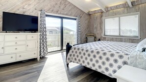 Una camera da letto con un letto, una TV, una cassettiera e una finestra con persiane.
