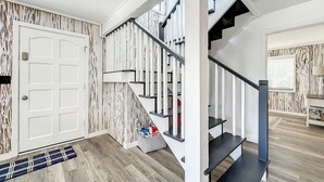 Una scala moderna con finitura in legno, una porta bianca e un tappeto che conduce a una stanza con una finestra.