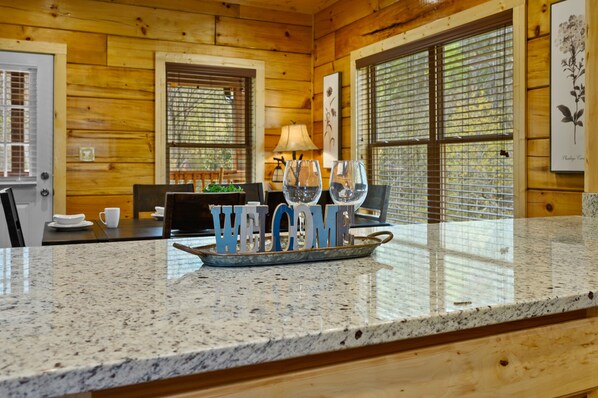 A kitchen counter with a welcome sign, a coffee table, and a dining table with chairs.