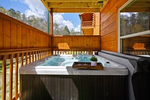 A wooden deck with a hot tub, two glasses, and a potted plant.