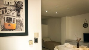 Una stanza moderna con un letto, un'area pranzo con sedie, un tavolo e un quadro appeso al muro.