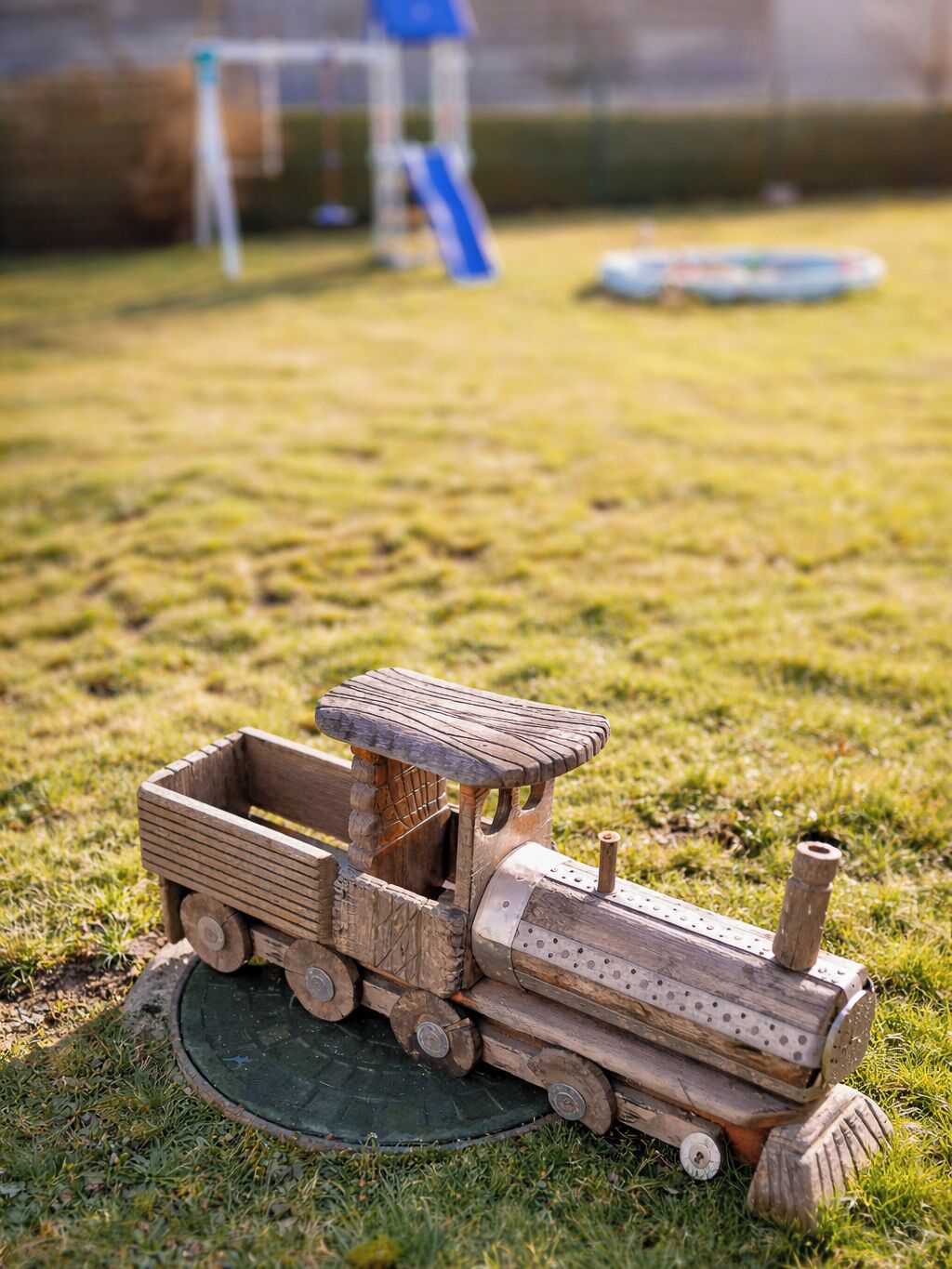 Ein hölzernes Spielzugfahrzeug auf einer grünen Wiese.