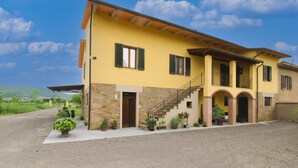 Una casa de dos pisos con fachada de piedra, un porche y una escalera que conduce al piso superior.