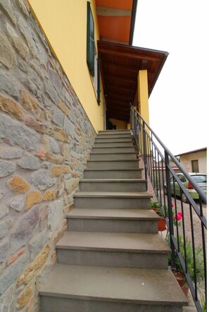 Stairs lead to the entrance of a building with a car parked in the background.