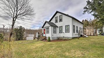 A two-story house with a front porch, a small front yard, and a driveway.