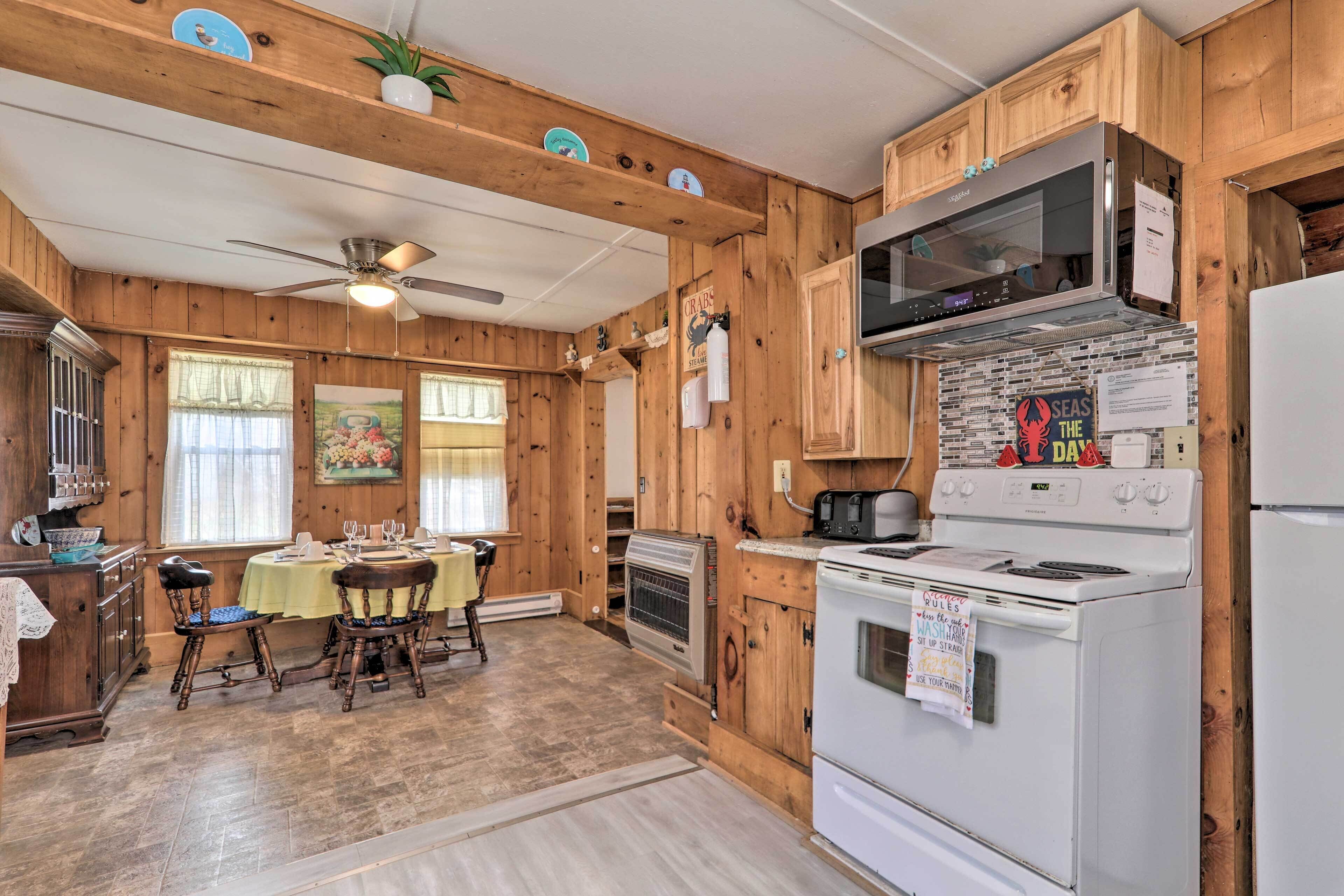 Une cuisine aménagée dans le style d’un chalet en bois, avec une table à manger pour quatre personnes, une cuisinière, un four à micro-ondes et un réfrigérateur.