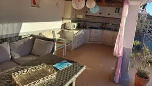 A cozy kitchen with a wooden ceiling, a dining area with a table and chairs, and a small kitchenette.