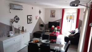 A modern living room with a dining area, a flat-screen TV, and a sofa.