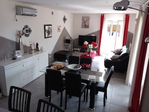 Uma sala de estar moderna com área de jantar, televisão de tela plana e sofá.