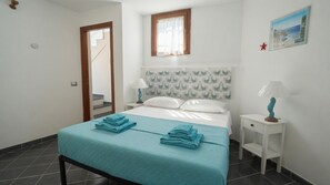 Ein Schlafzimmer mit einem Bett, zwei Nachttischen, einem Fenster und einer Tür.