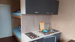 A compact kitchenette with a stove, sink, and storage cabinets. - Cozy tiny house on the Greifswalder Bodden (Brünzow)