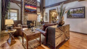 A spacious living room with a fireplace, leather furniture, and artwork on the walls.