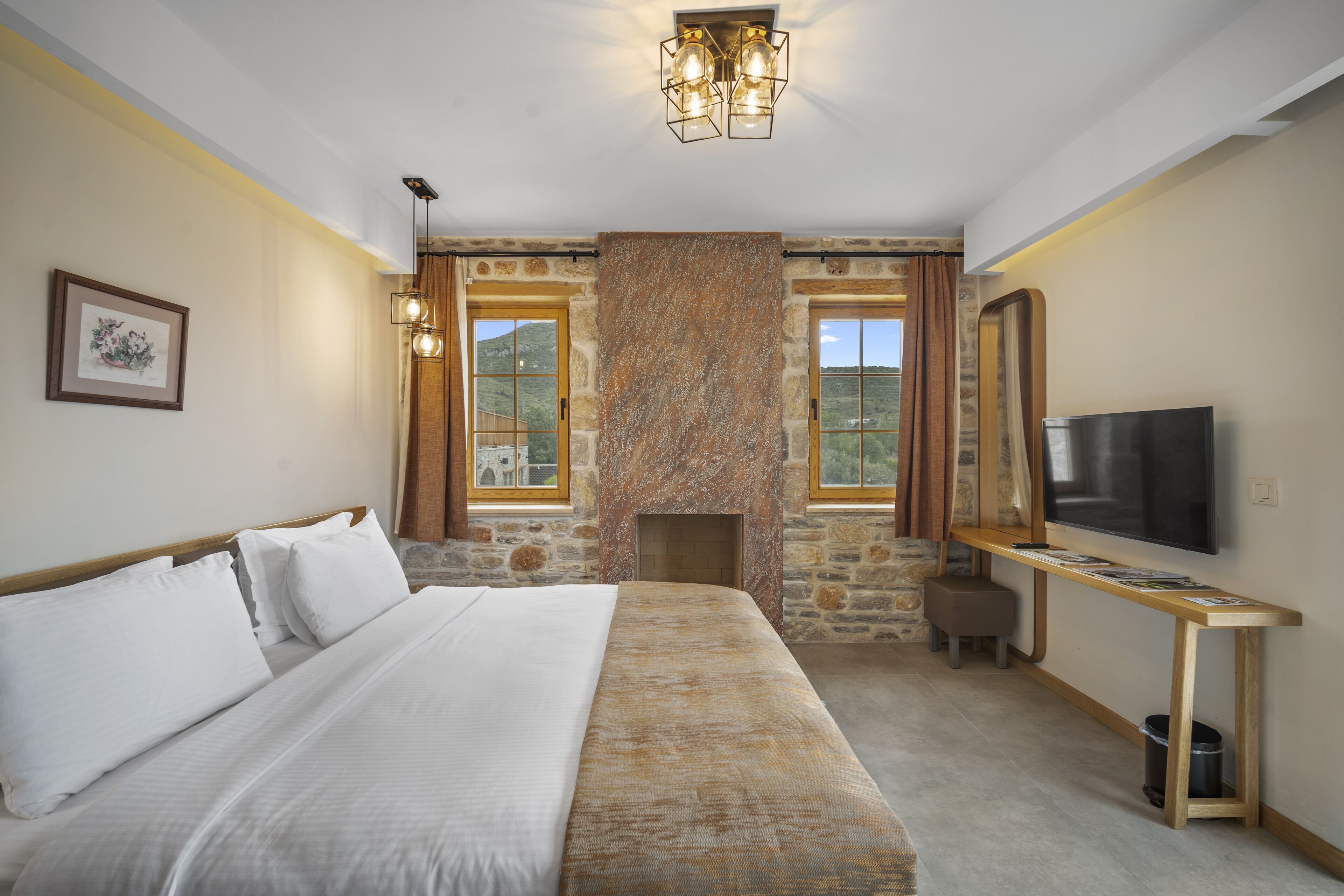 Una habitación de hotel con una cama grande, una chimenea de piedra, un televisor y una ventana con cortinas.