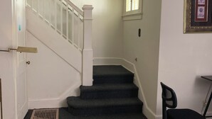 Una escalera con barandales blancos y un rellano alfombrado.