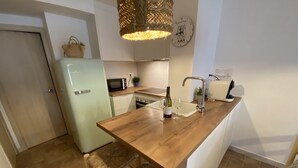 A modern kitchen with a wooden countertop, a refrigerator, a microwave, a sink, and a hanging light fixture. - Modern apartment in Llafranc with A/C. No view (Llafranc)