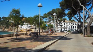 A coastal promenade with benches, a lamp post, and a row of buildings along the water. - Modern apartment in Llafranc with A/C. No view (Llafranc)