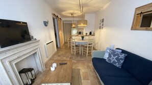 A living room with a fireplace, a TV, a sofa, and a dining area in the background. - Modern apartment in Llafranc with A/C. No view (Llafranc)