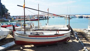 A boat docked at a sandy beach with other boats in the background. - Modern apartment in Llafranc with A/C. No view (Llafranc)