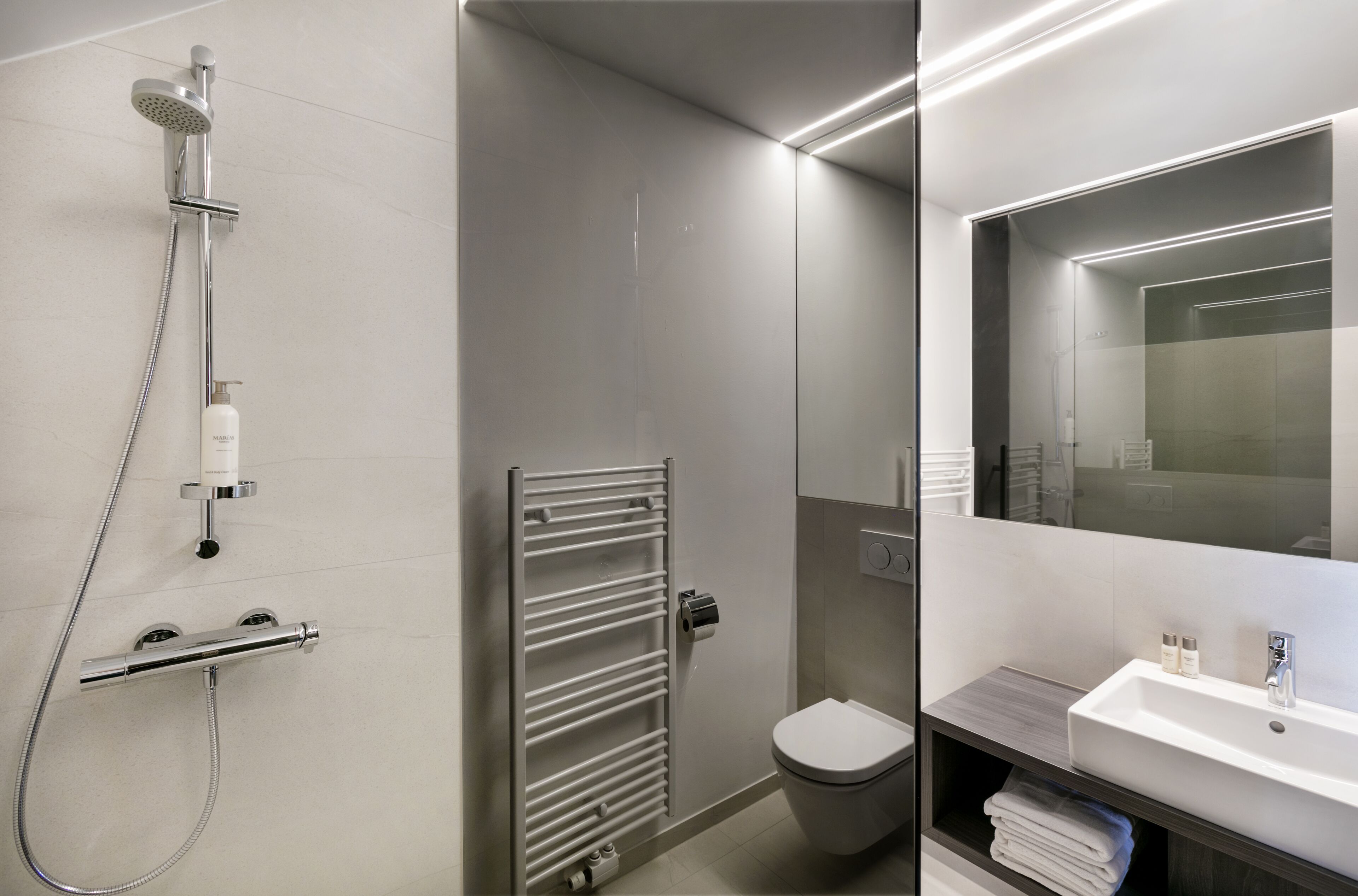 Une salle de bain moderne équipée d’une douche, de toilettes et d’un lavabo.