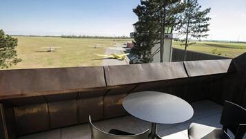 A balcony with a view of a grassy field and a small aircraft.