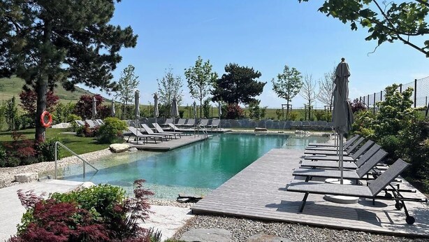 Una piscina con sillas de descanso y un muelle de madera.