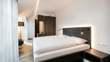 A modern hotel room with a large bed, a bedside table, and a built-in wardrobe.