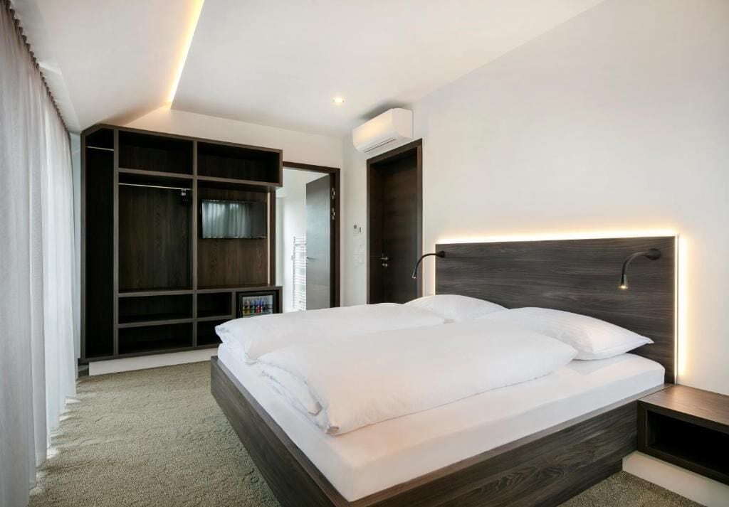 Une chambre d’hôtel moderne dotée d’un grand lit, d’une armoire intégrée et d’une table de chevet.