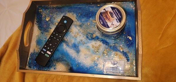 A tray with a remote control and a container of Bucanari Dulces.