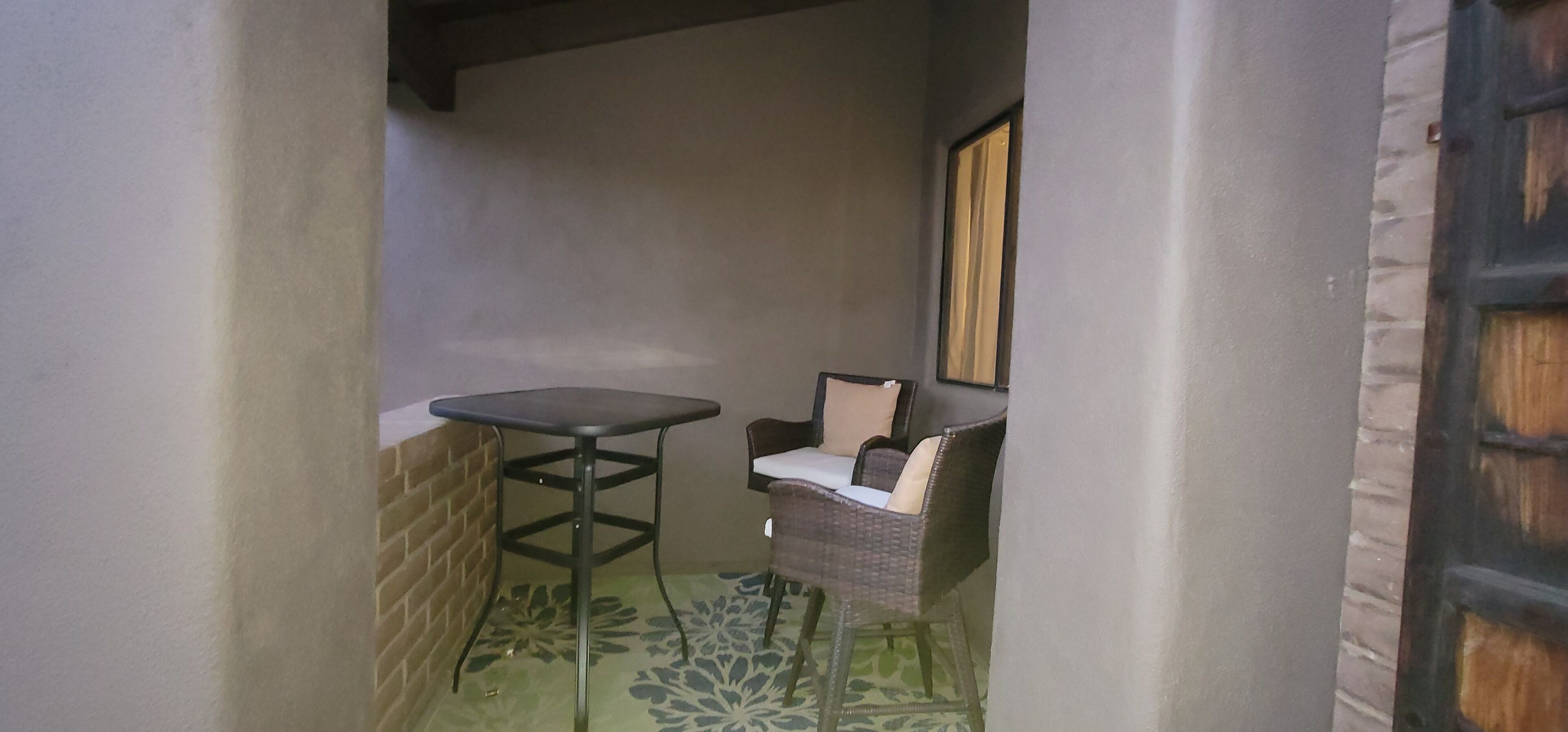 A small, enclosed outdoor area with a table and a wicker chair.