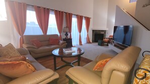 A living room with a sofa, armchairs, a coffee table, and a flat-screen TV. - New house with fresh design available in Olsen TH. (Tucson)