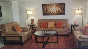A living room with a sofa set, two side tables, a coffee table, and a wall art piece. - New house with fresh design available in Olsen TH. (Tucson)