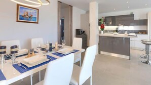 Un'area pranzo moderna con tavolo apparecchiato per quattro, una cucina con mobili scuri e un'ampia finestra.