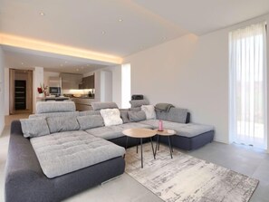 A modern living room with a grey sectional sofa, a small round coffee table, and a patterned rug.