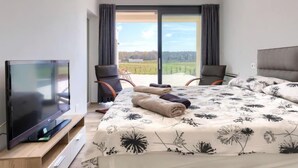 Una moderna camera d'hotel con un ampio letto, una televisione a schermo piatto e un balcone con vista panoramica.