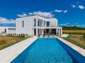 A modern two-story house with a swimming pool in front.
