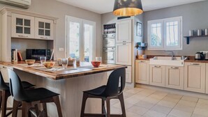 Una cocina moderna con una isla central, armarios blancos y una lámpara colgante.