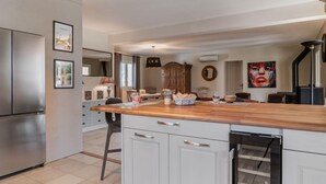 Una cocina moderna con una isla central, armarios blancos y un refrigerador de acero inoxidable.