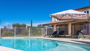 Una piscina con sillas de descanso y un área de patio techada.