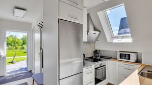 Una cucina moderna con mobili bianchi, forno integrato, microonde e un'ampia finestra con vista sull'esterno.