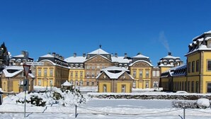 Una fila di edifici gialli con tetti imbiancati dalla neve e un cielo azzurro intenso.